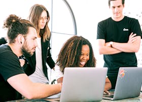 A diverse group of young professionals collaborating enthusiastically in a bright, modern workspace.