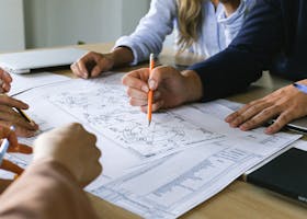 Team working on engineering plans, discussing ideas at an office meeting.